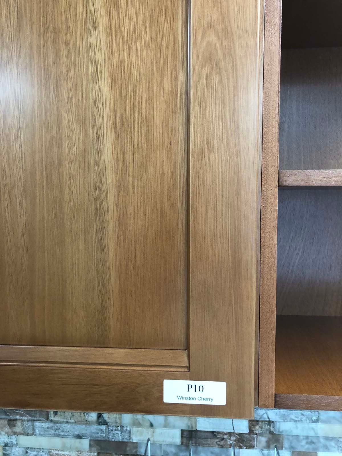 Wooden cabinet with a small white label on the lower edge, next to an open shelving compartment.
