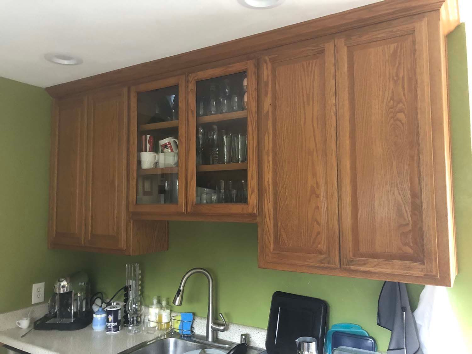 Kitchen with wood cabinets, green walls, a sink, and small appliances on the counter.