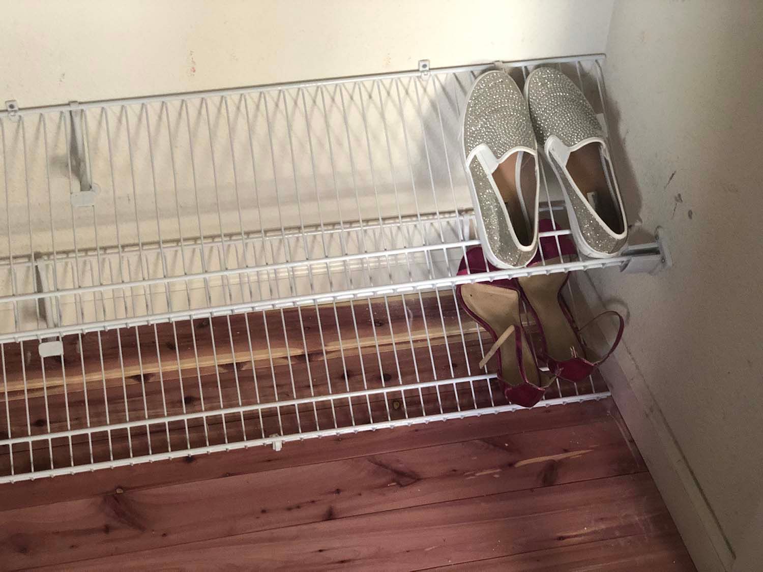 White wire shoe rack in a closet with a pair of gray sneakers on the top shelf