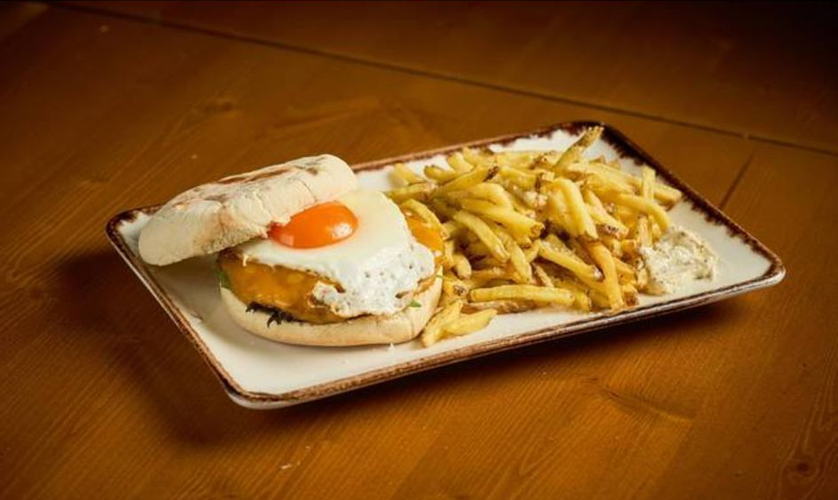 Sanduíche com ovo frito e batatas fritas em uma bandeja retangular.