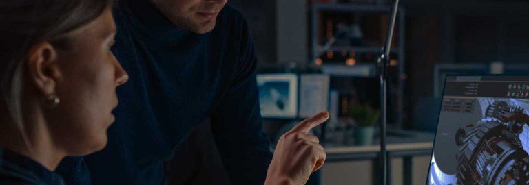 A man and a woman are looking at a computer screen.
