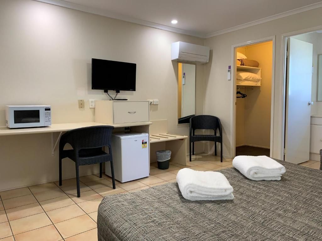 Hotel room with two beds, desk, TV, microwave, and open bathroom and closet doors