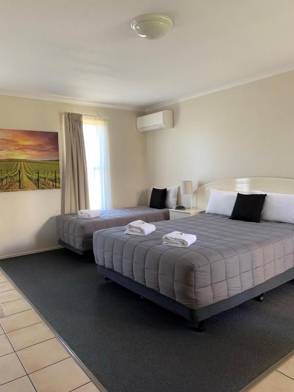 Hotel room with two queen beds, gray bedding, tiled floor, and a landscape painting on the wall