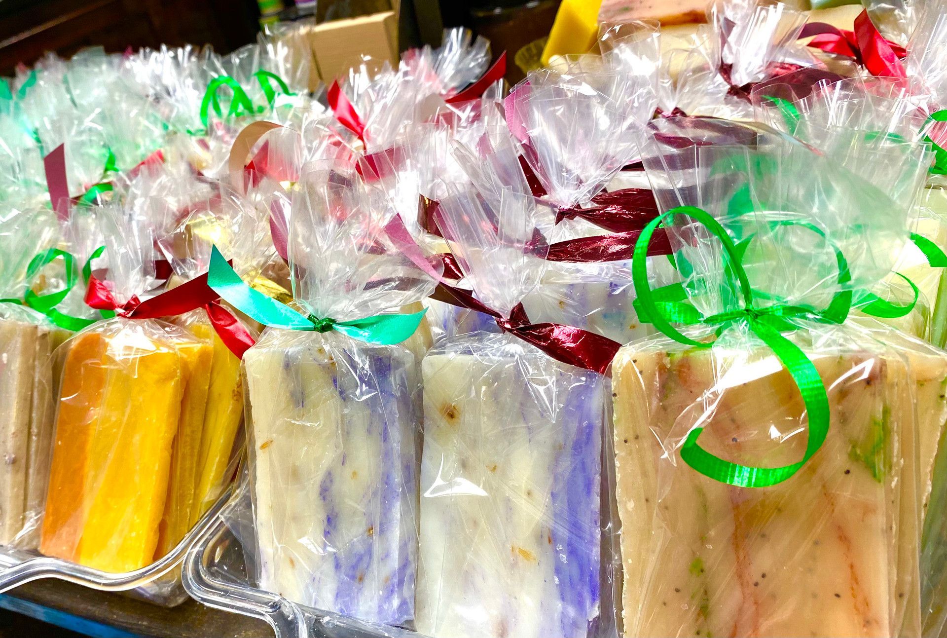 A bunch of soaps wrapped in plastic with ribbons on a table.