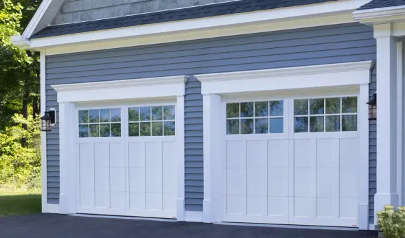 White house with a gray garage door, brown door, and brick driveway.