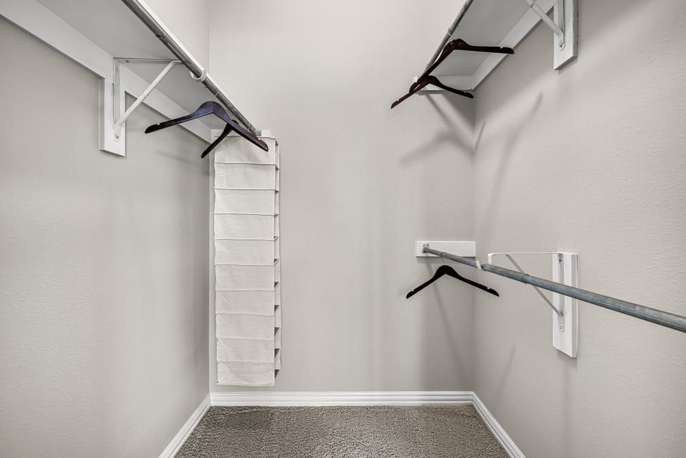 A walk-in closet with a lot of space and hangers at Marquis at Silver Oaks in Grapevine, TX.