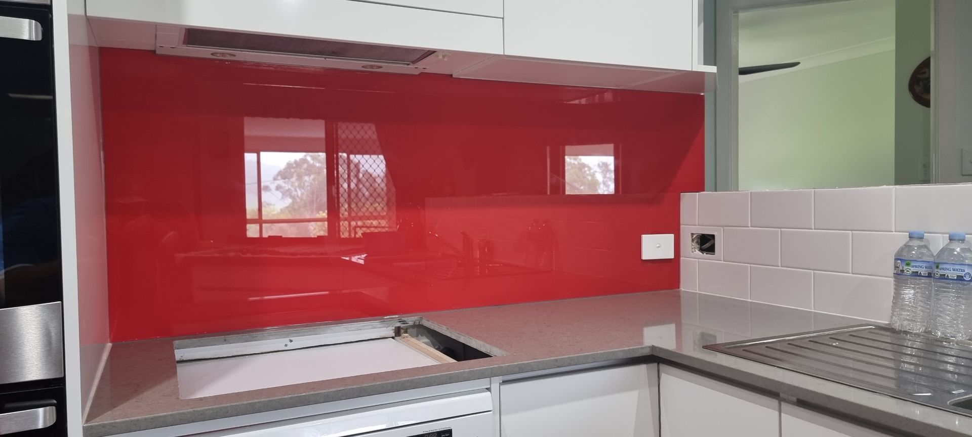 A Kitchen With A Red Backsplash And White Cabinets — Nambucca Glass in Nambucca Heads, NSW