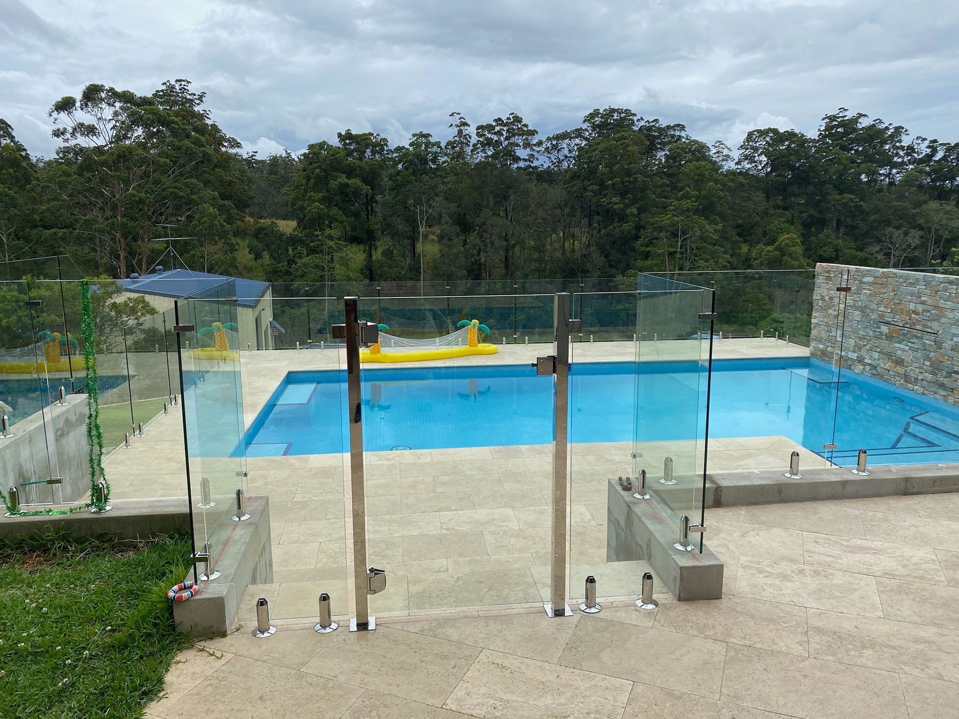 A Large Swimming Pool With A Glass Fence Around It — Nambucca Glass in Nambucca Heads, NSW