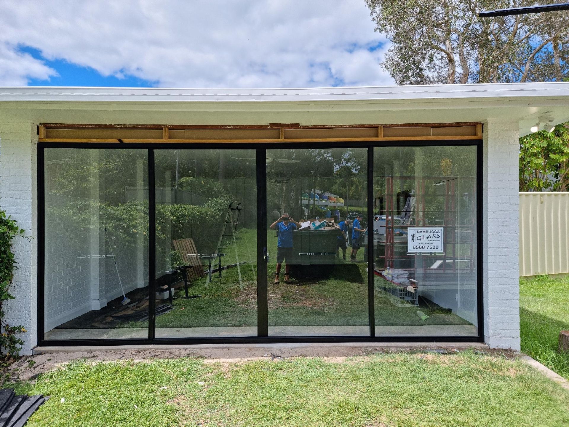 A White House With Sliding Glass Doors Is Sitting On Top Of A Lush Green Lawn — Nambucca Glass in Nambucca Heads, NSW