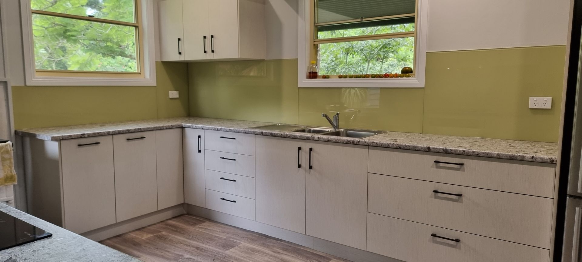 A Kitchen With White Cabinets, Granite Counter Tops, A Sink And A Window — Nambucca Glass in Nambucca Heads, NSW