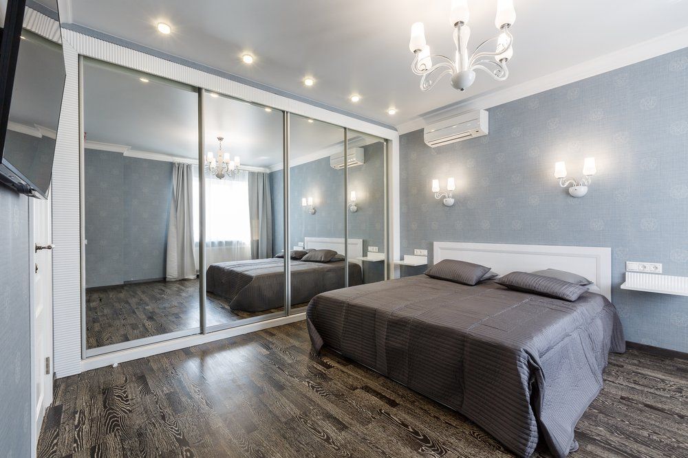 A Bedroom With A Large Mirrored Wardrobe And A Bed — Nambucca Glass in Nambucca Heads, NSW