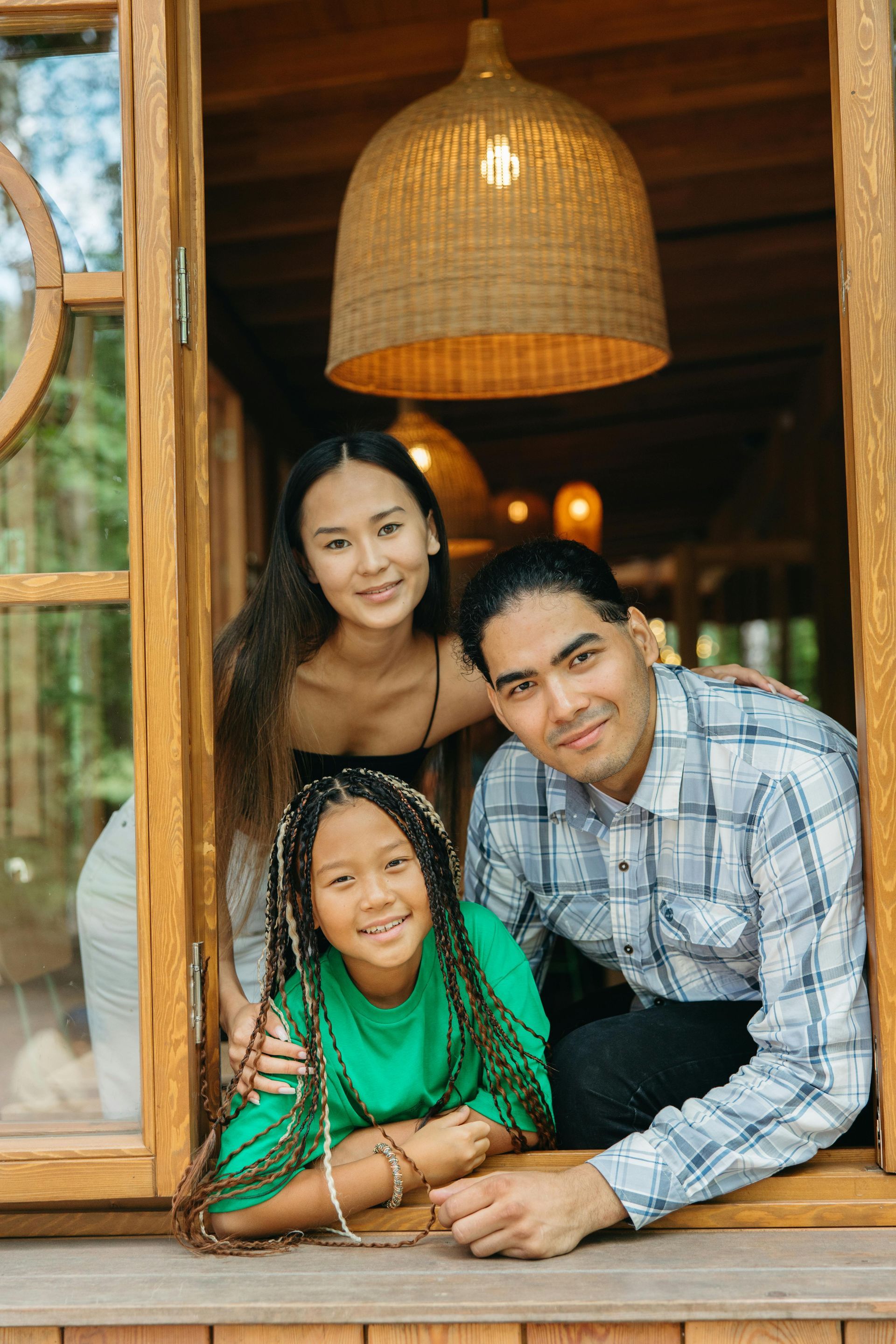Family standing together in a loft-style kitchen, looking at a phone near a hanging light.
