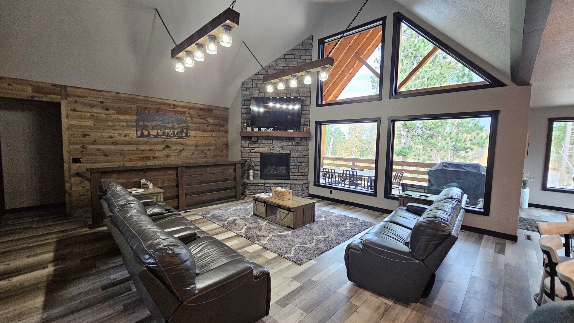 Living room with leather couches, fireplace, large windows, and wood accents.