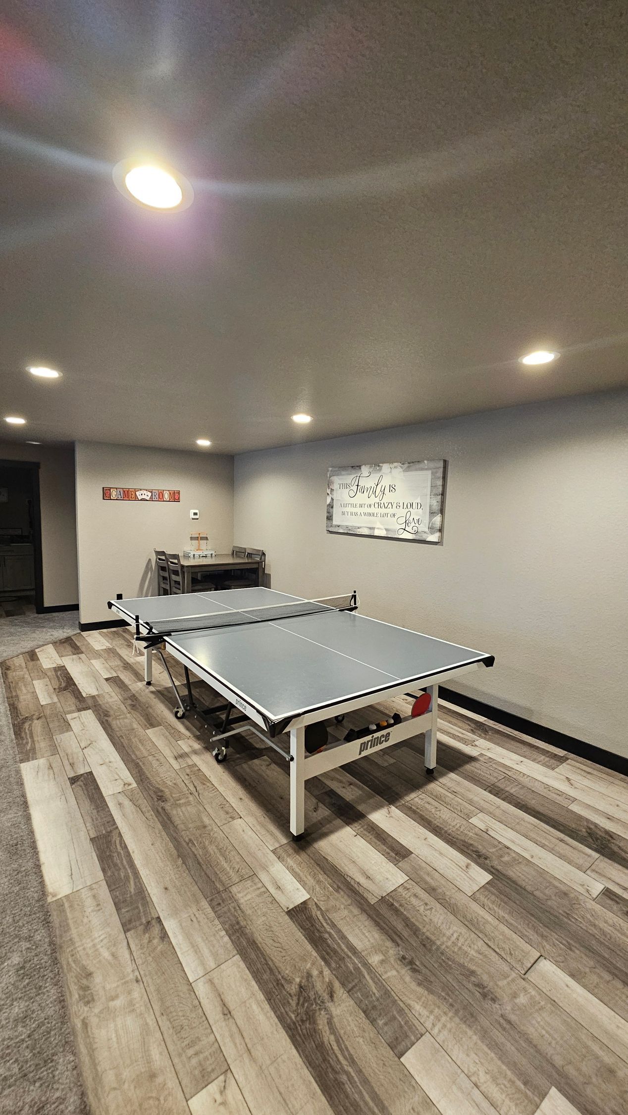 Ping pong tables in a room with wood-look flooring and recessed lighting.