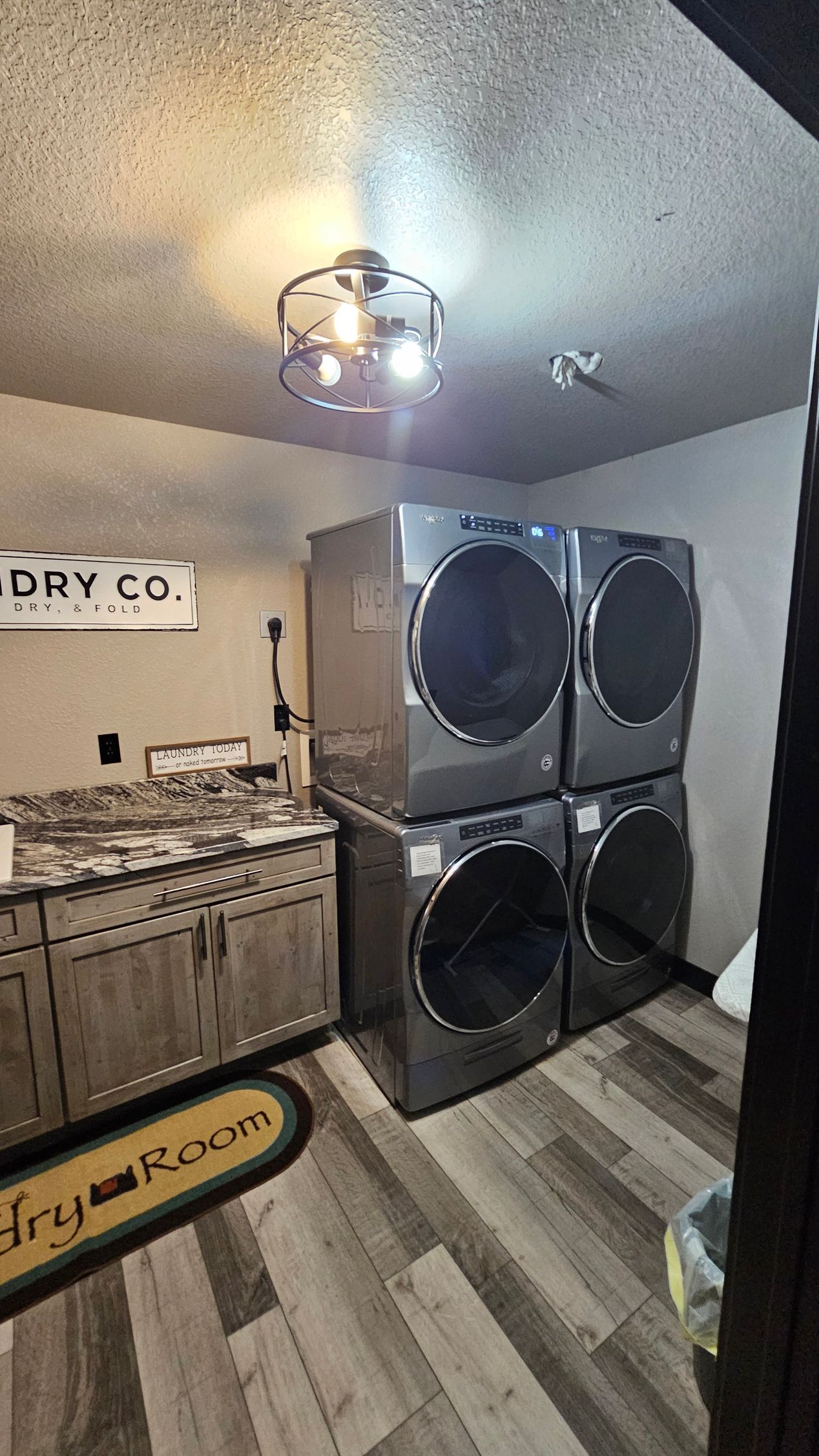Laundry room with stacked gray washers/dryers, cabinets, and a 