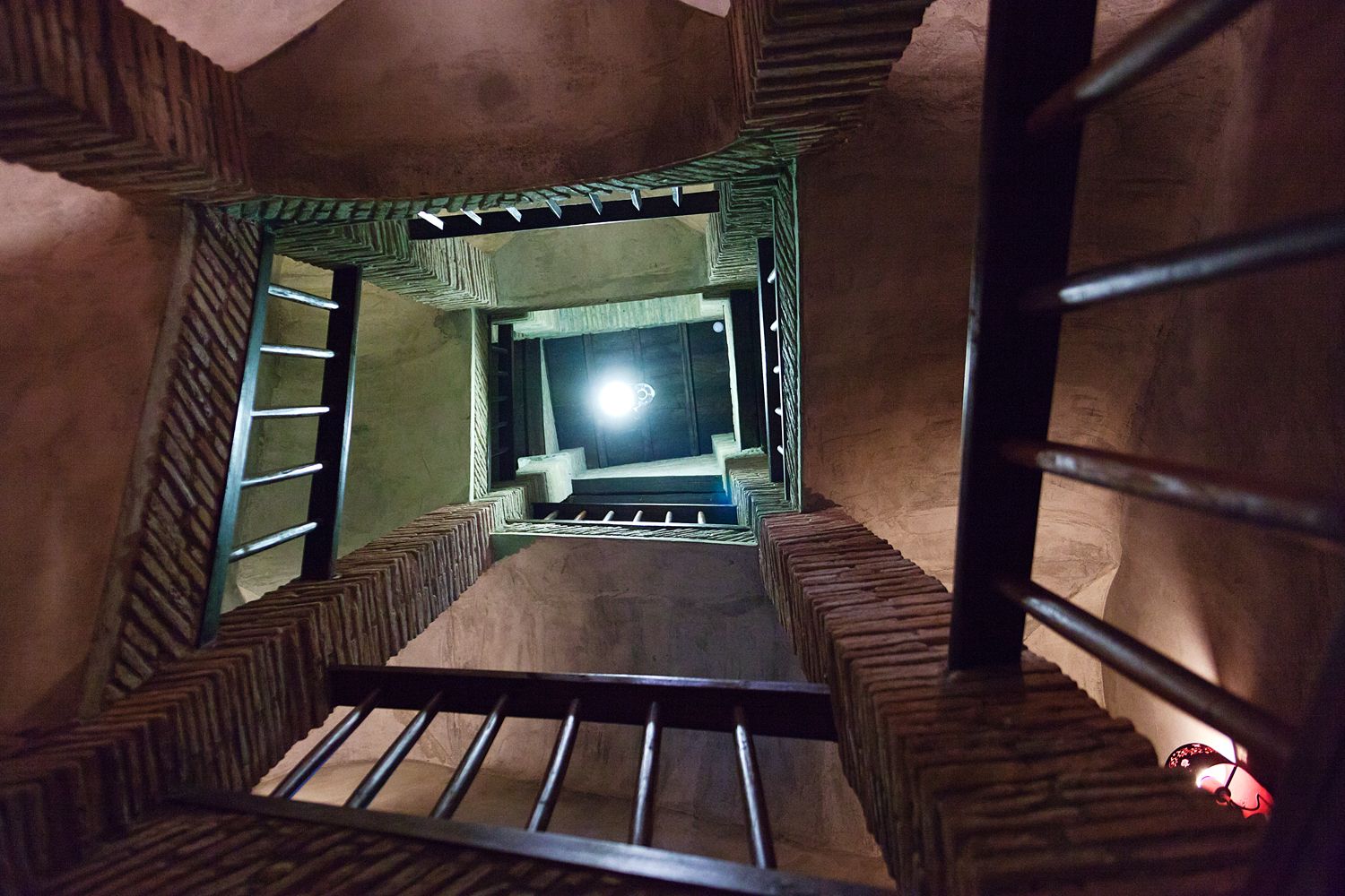 Looking up at a staircase with a ladder in a dark room.