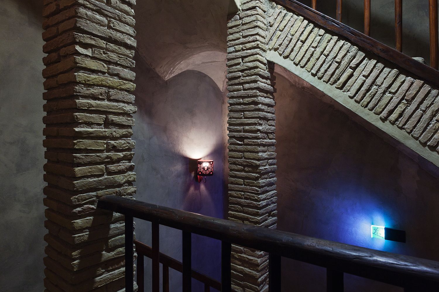 A staircase with brick columns and a blue light on the wall
