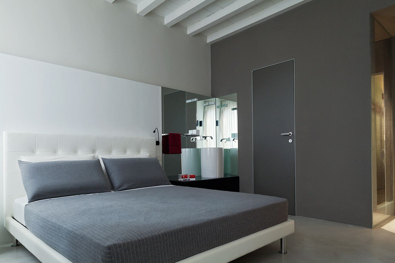A bedroom with a bed and a bathroom in the background