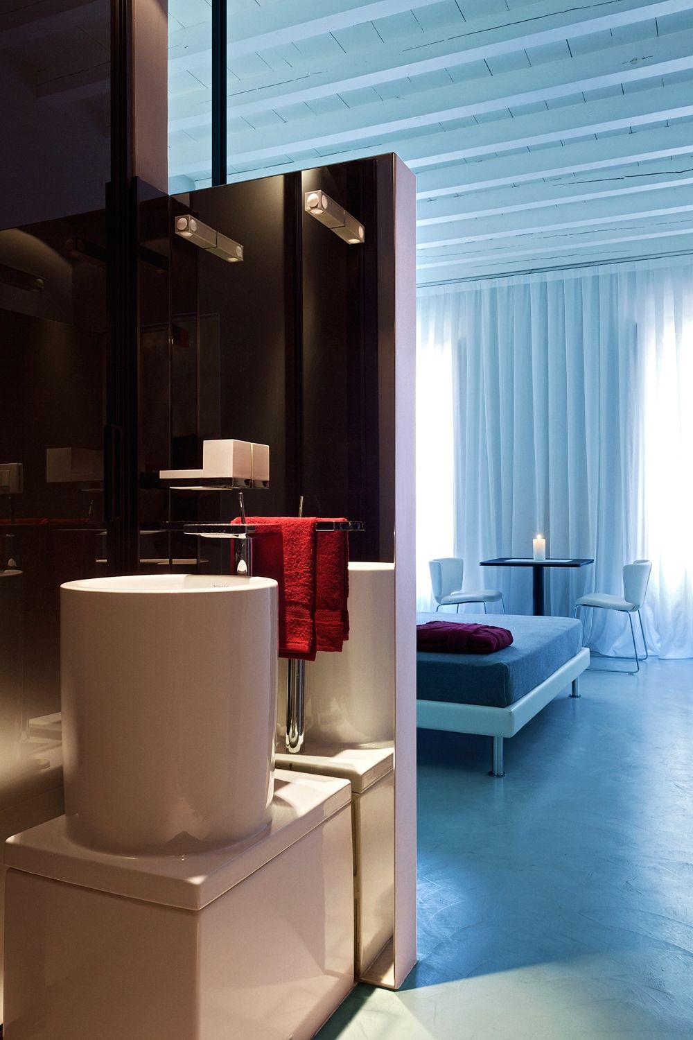 A bathroom with two sinks and a bed in the background