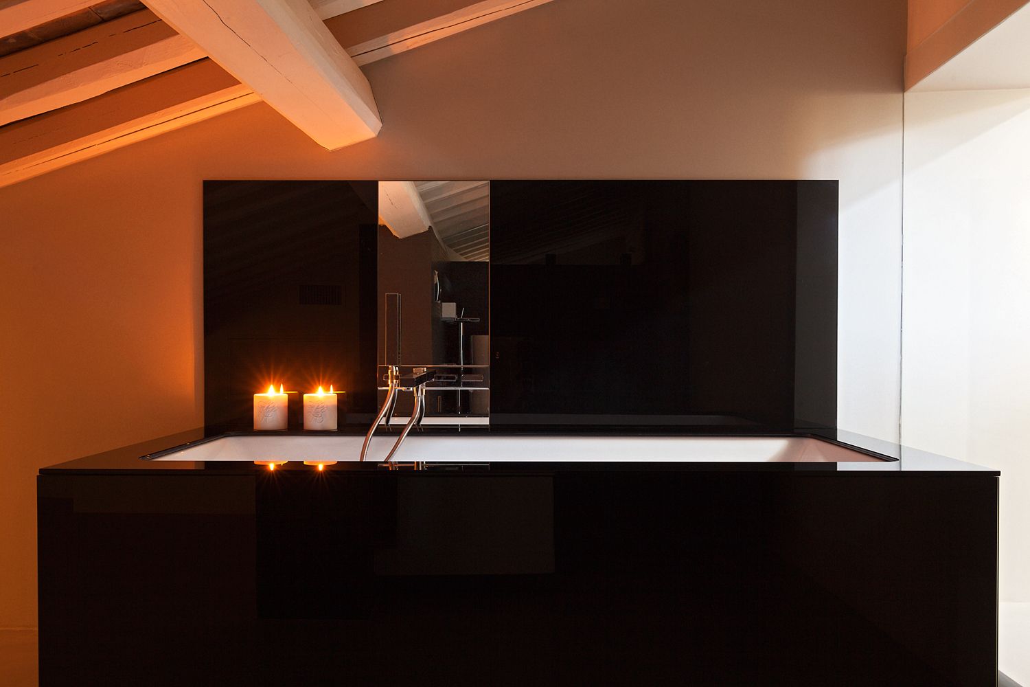 A bathroom with a black bathtub and two candles