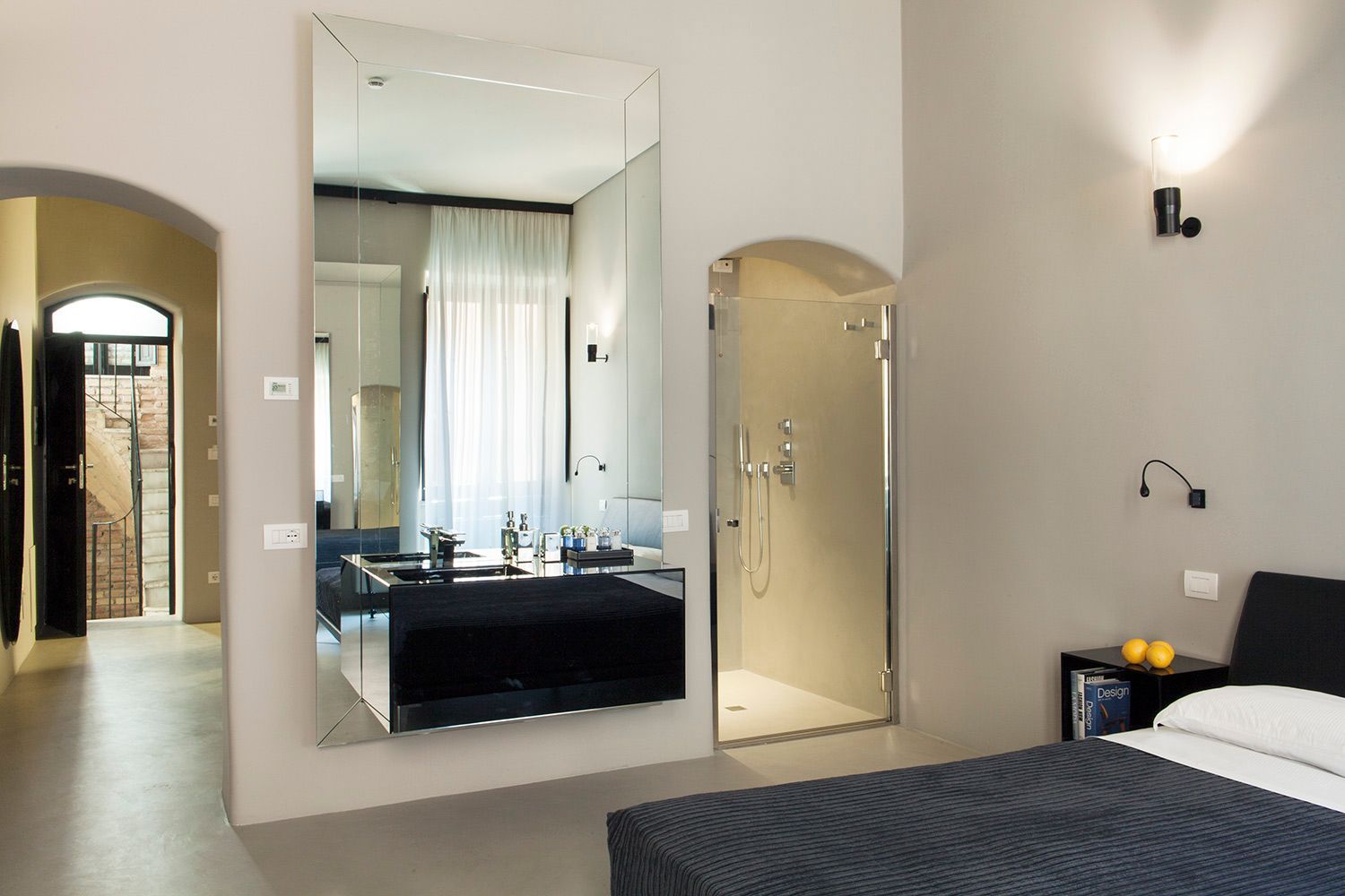 Una camera da letto con un grande specchio sul muro e una cabina doccia.
