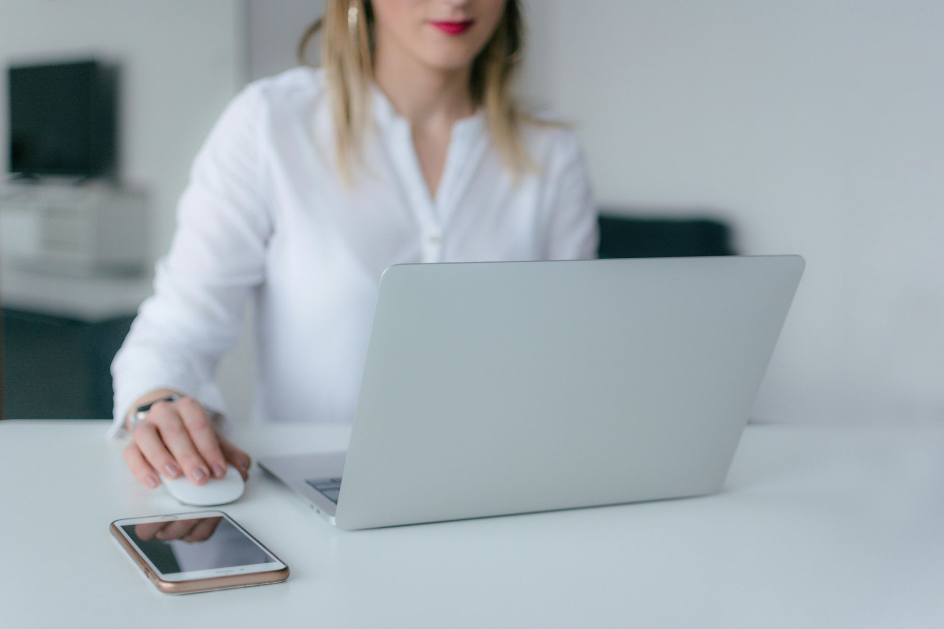 A woman is sitting at a desk using a laptop computer.