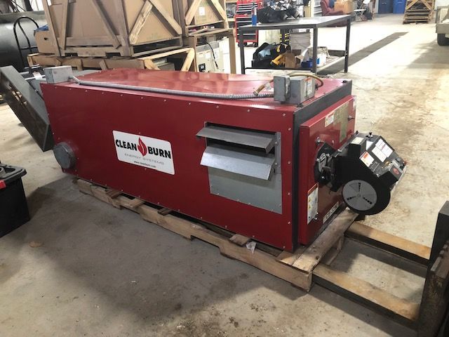 A red machine is sitting on a wooden pallet in a garage.