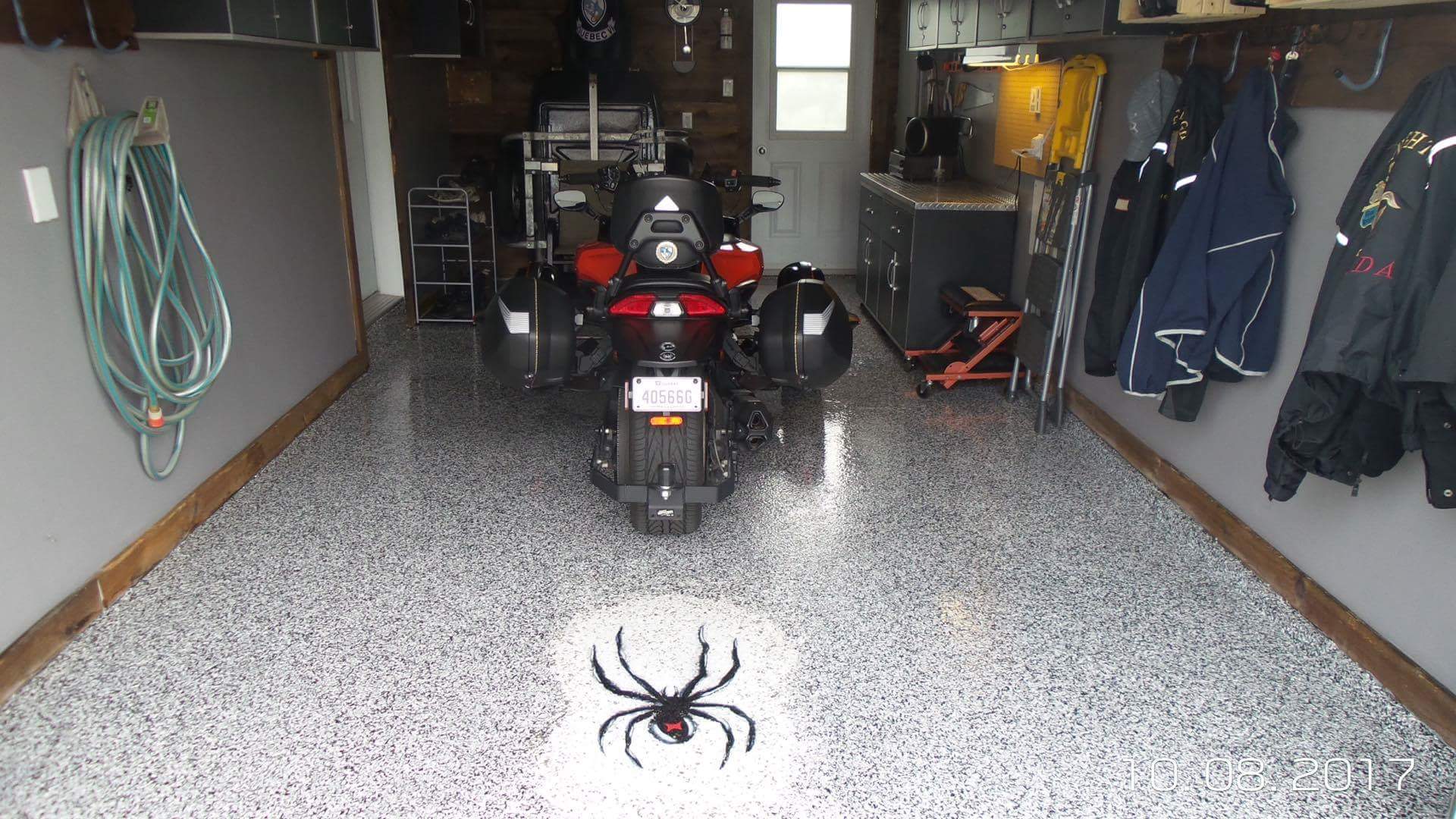 Une moto est garée dans un garage avec une araignée peinte sur le sol