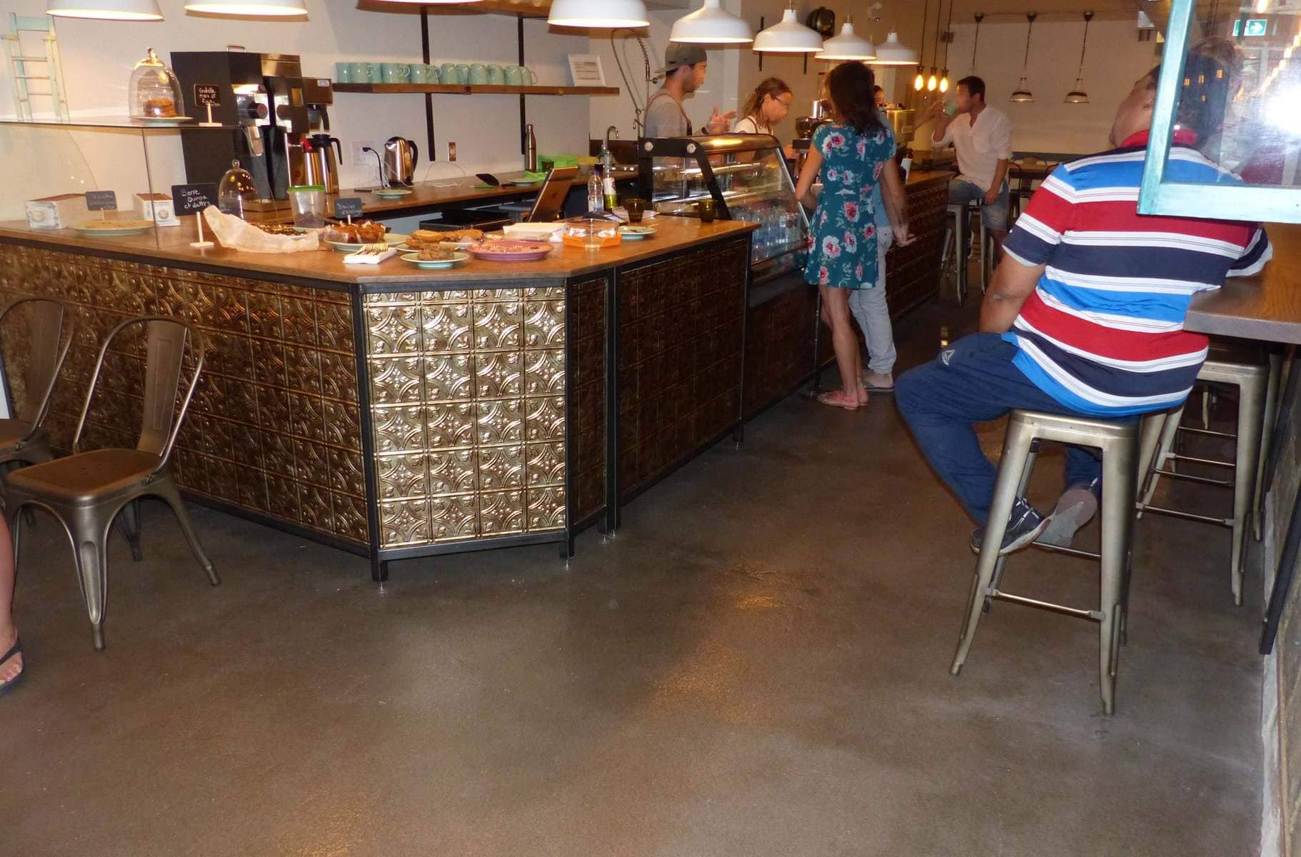 Un homme en chemise rayée est assis sur un tabouret dans un restaurant