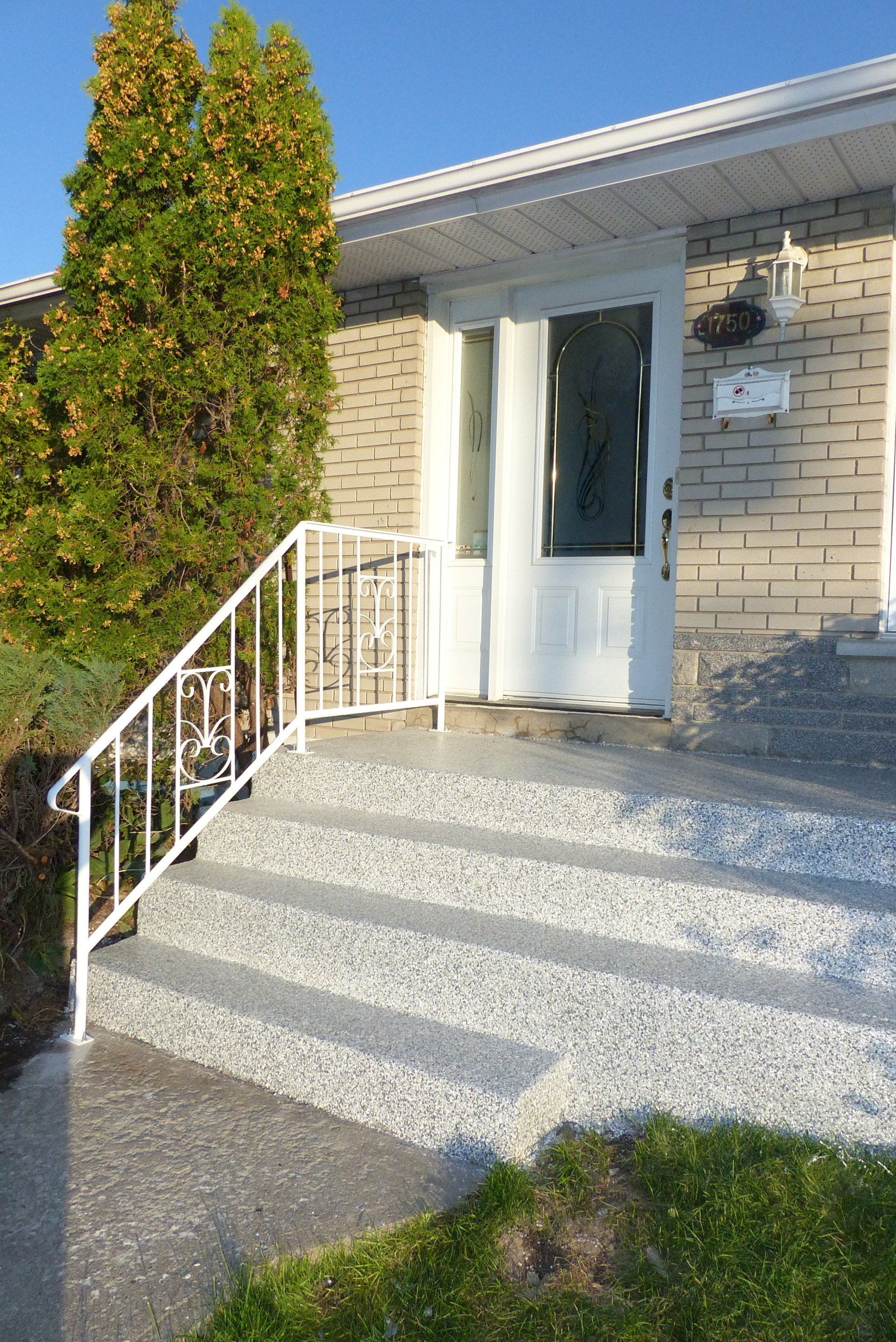 Une maison en briques avec une porte blanche et des escaliers