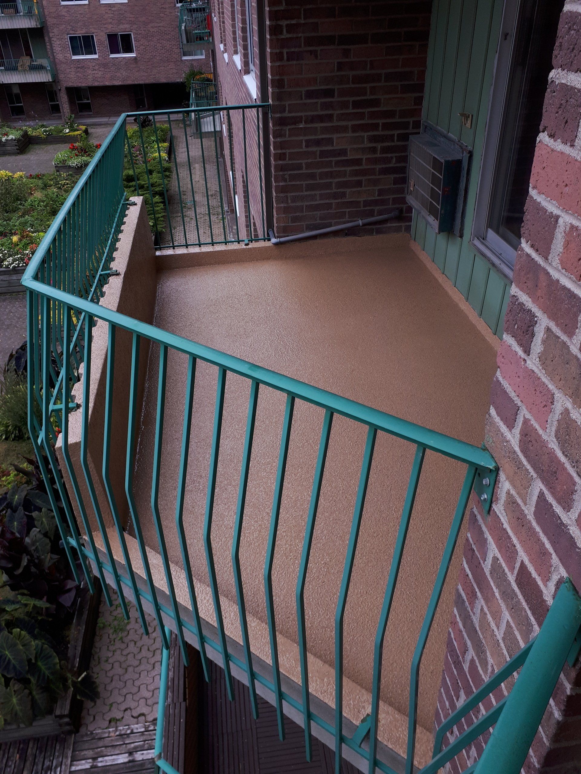 Un balcon avec une balustrade verte sur un bâtiment en briques.
