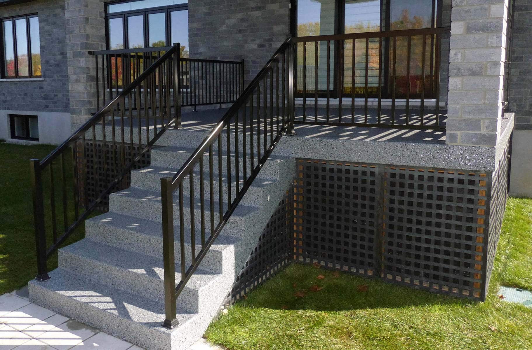 Un escalier menant à une maison avec une rampe en métal.