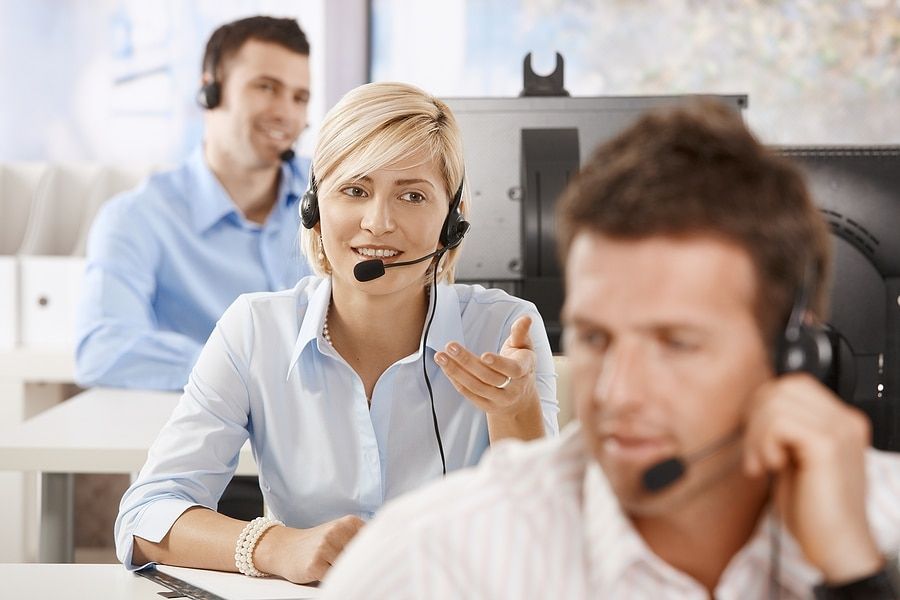 A woman wearing a headset is talking to a man in a call center.