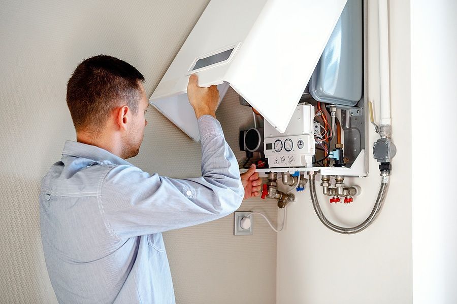 A man is fixing a boiler in a room.