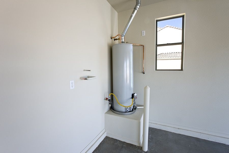 An empty room with a water heater and a window.