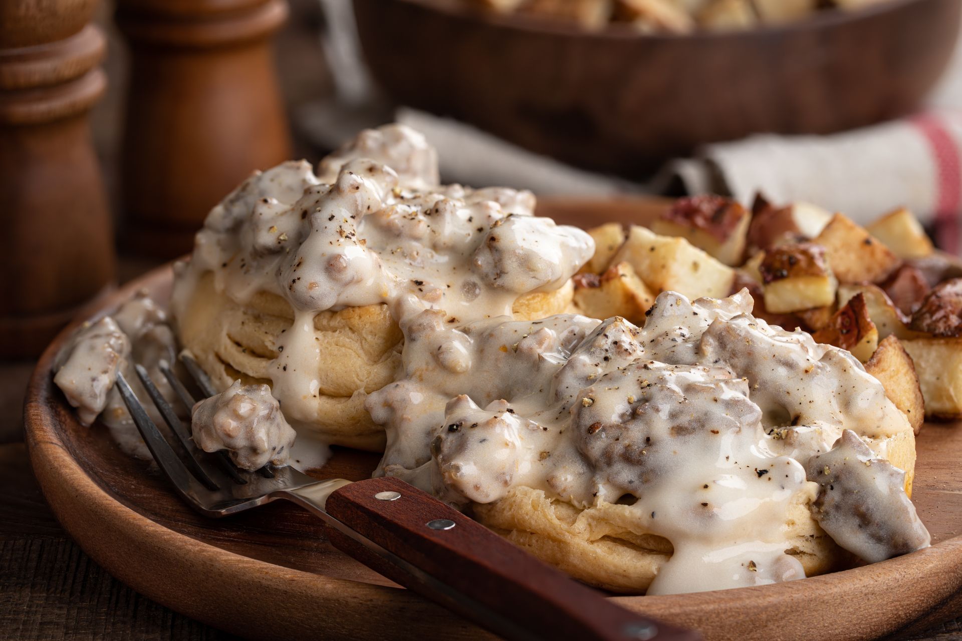 Breakfast plate with waffles, fried potatoes, and white gravy on a wooden table