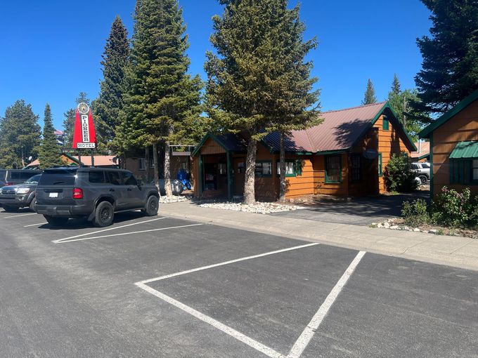 Cabins in a campground, brown exteriors, surrounded by trees, sunny day.