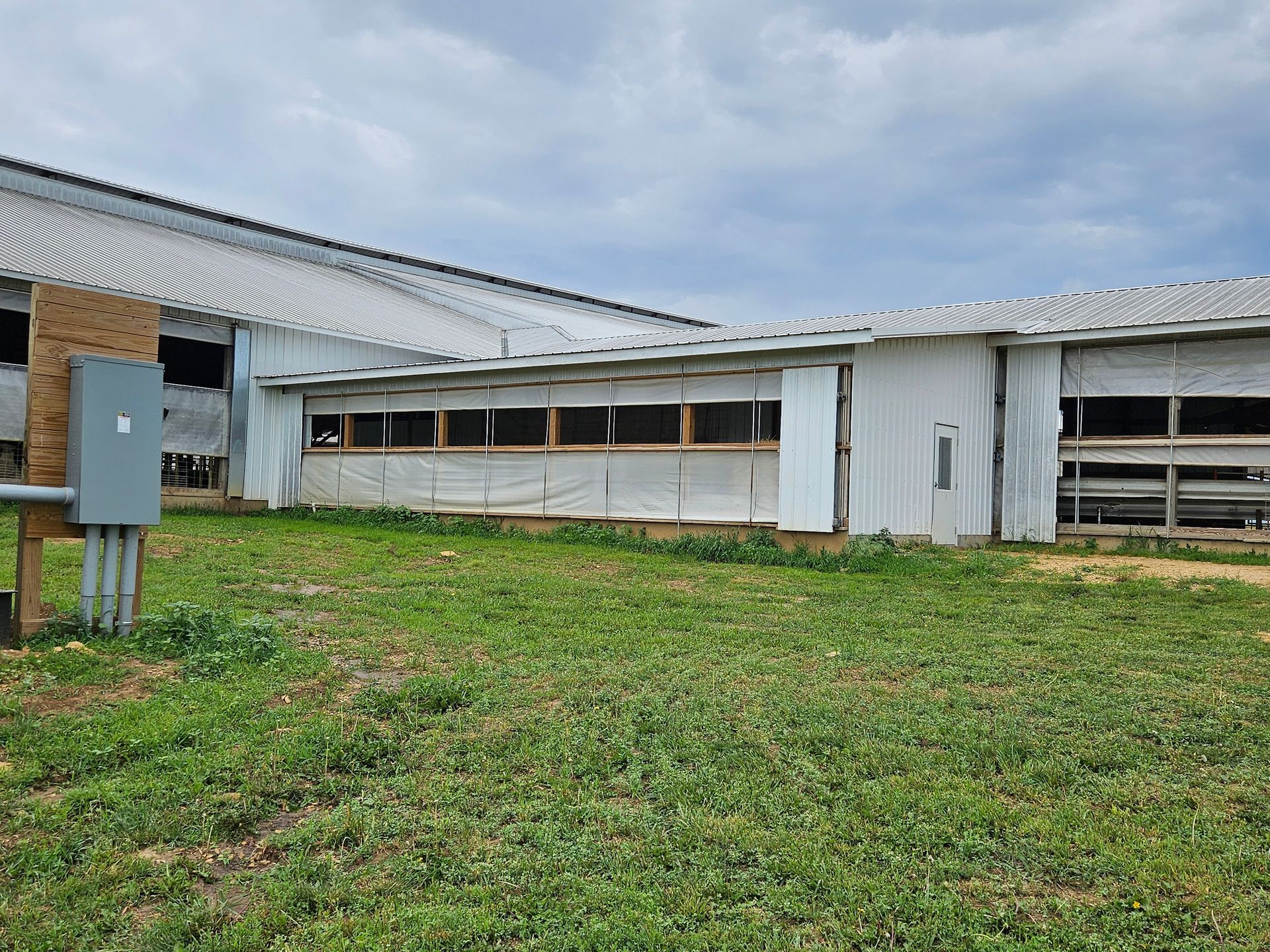 A large white building is sitting in the middle of a grassy field.