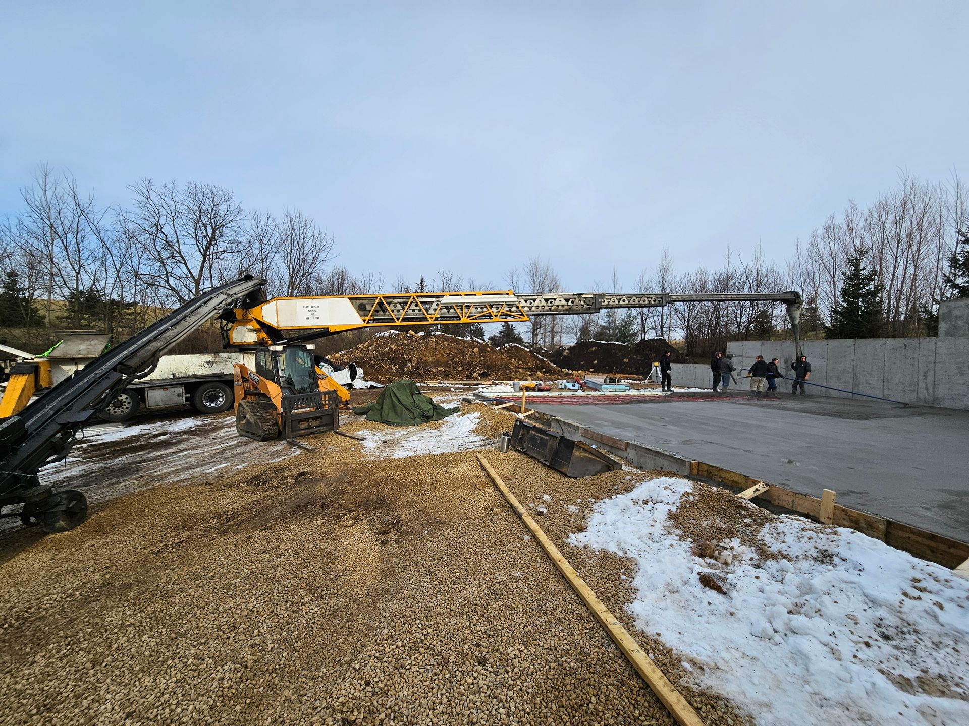 A construction site with a crane and a tractor in the snow.