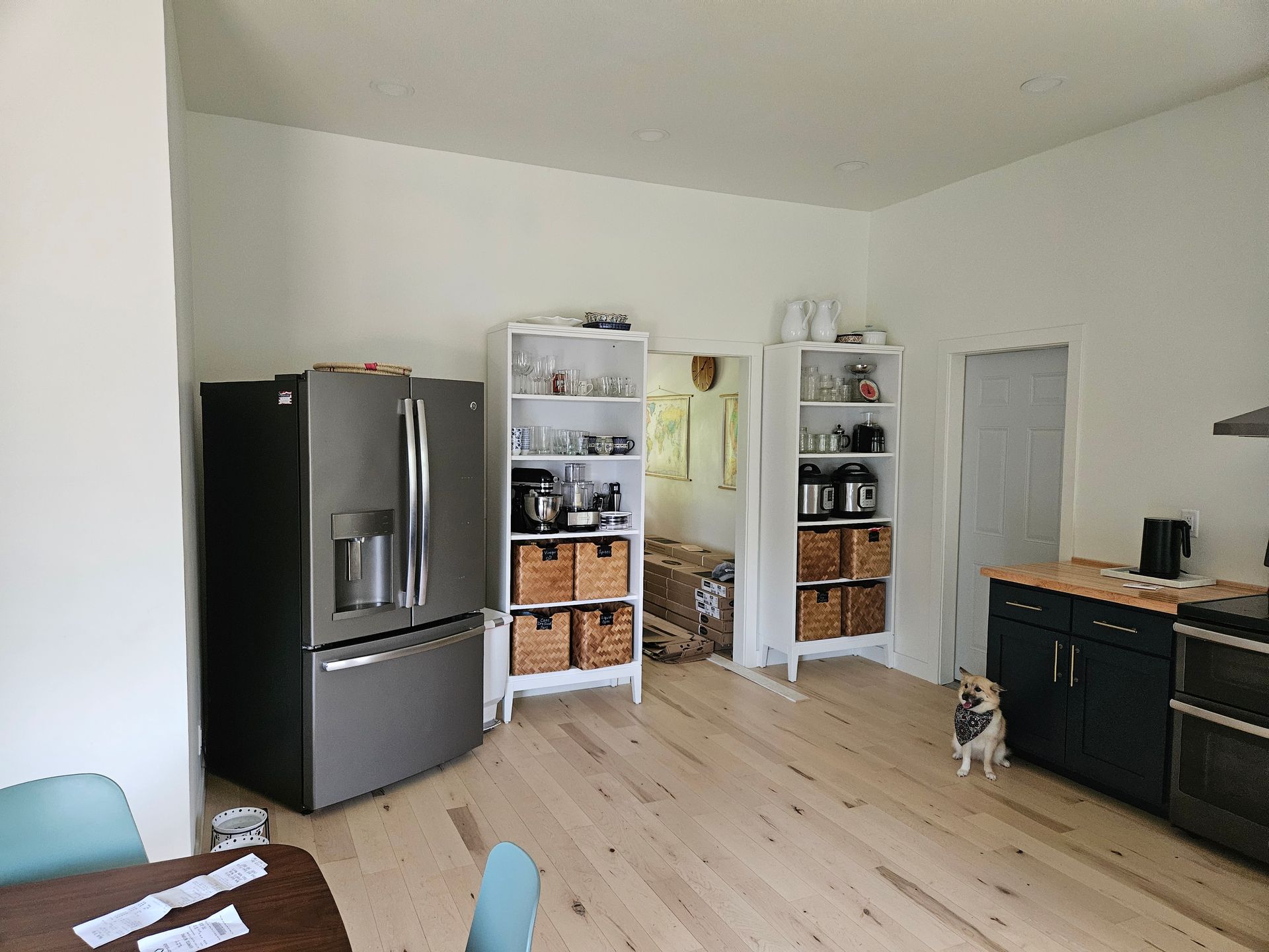 A dog is standing in a kitchen next to a refrigerator.