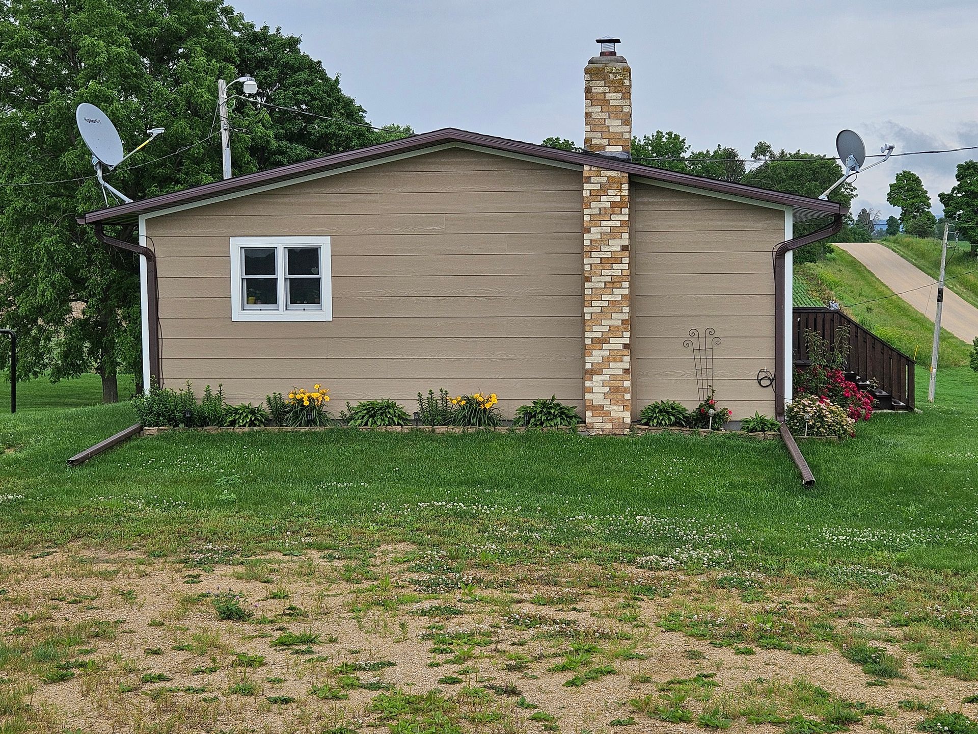 A small house with a chimney and satellite dishes on the side of it.