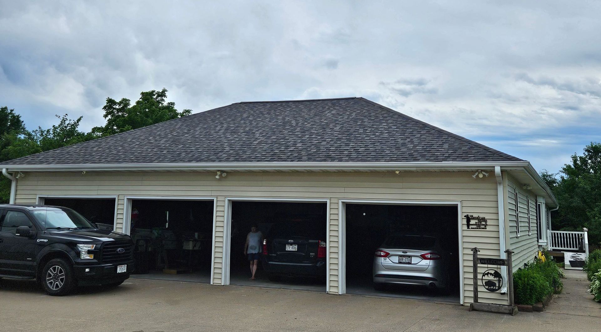 A large white garage with three cars parked in it.