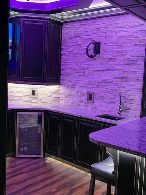 A kitchen with purple lights on the ceiling and a sink.