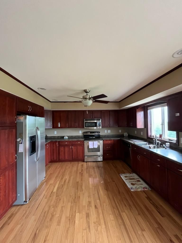 Kitchen with cherry-stained cabinets, stainless steel appliances, and wood flooring.