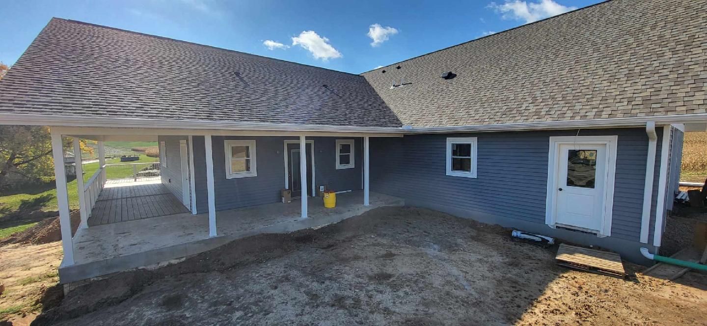 The back of a house with a porch and a carport.