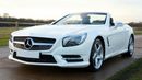 White Mercedes SL convertible parked on a road.