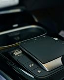 Black car interior control panel with a touchpad and silver accents.