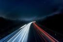 Long exposure of highway at night, with streaks of white and red car lights.