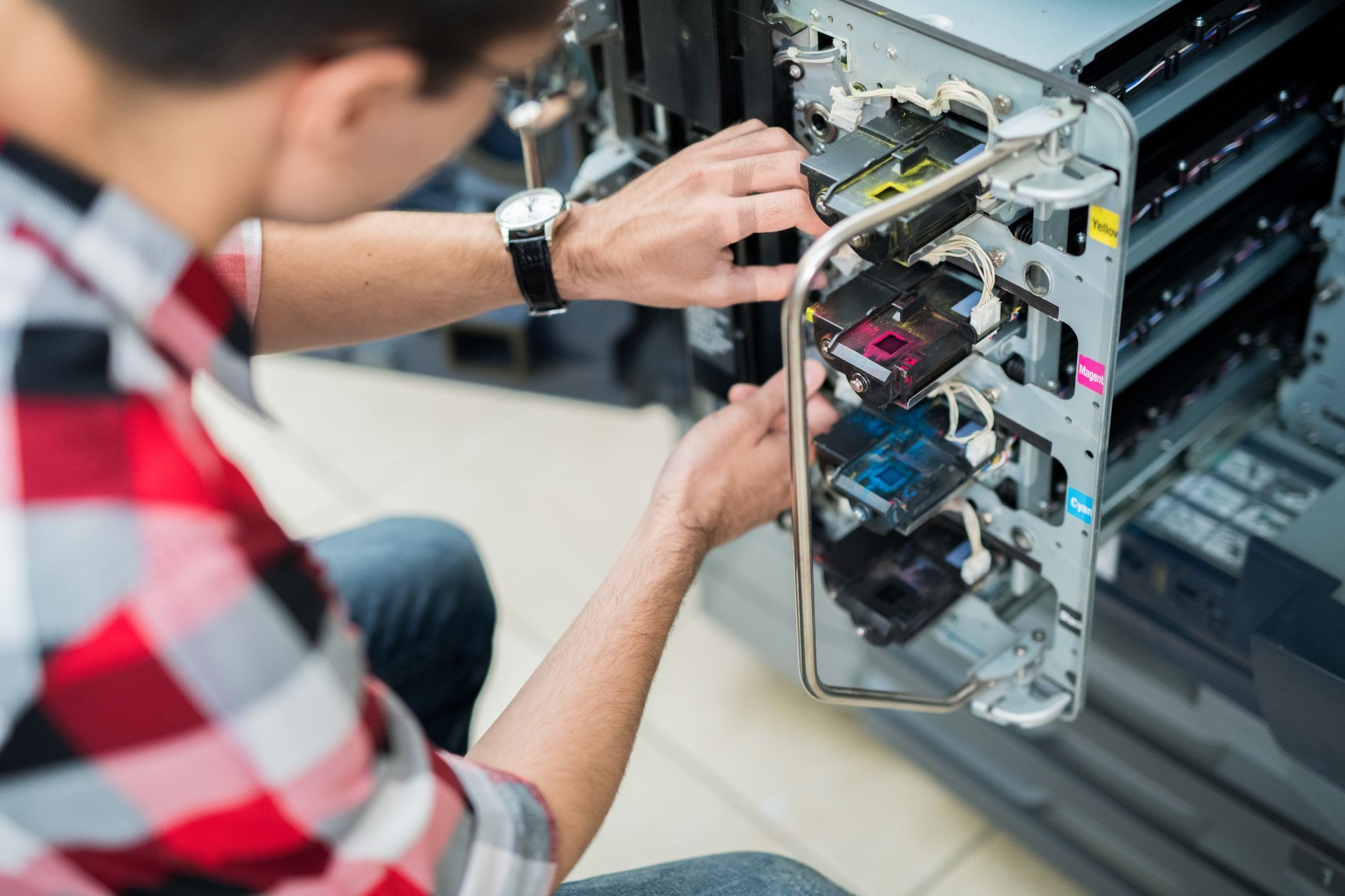 A man is working on a printer in a server room.