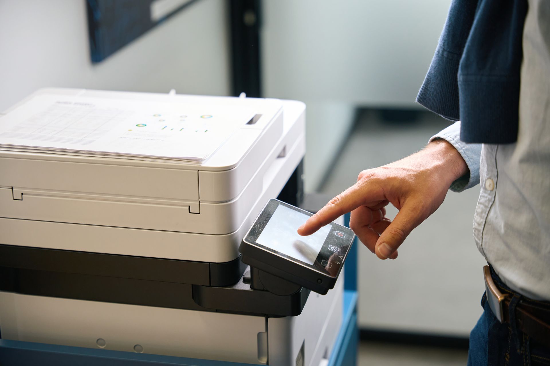 A man is pressing a button on a printer.